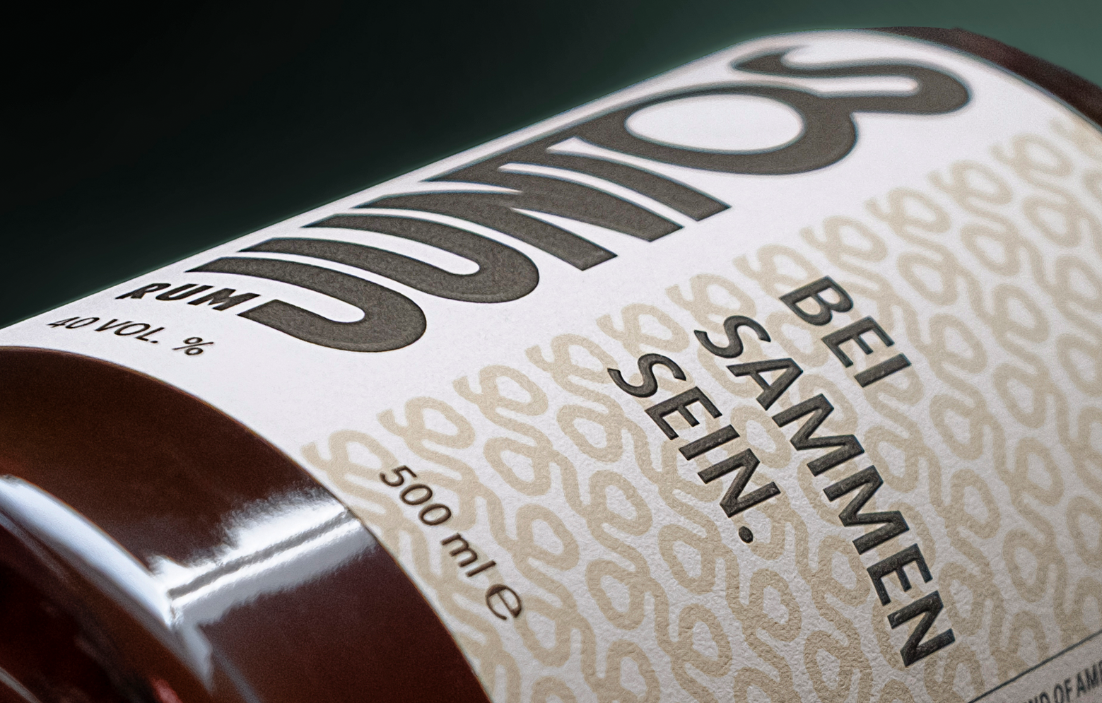 JUNTOS Rum Produktfoto. Ein Close-up von der Flasche, seitlich fotografiert in einem dunkelgrünen Setting.
