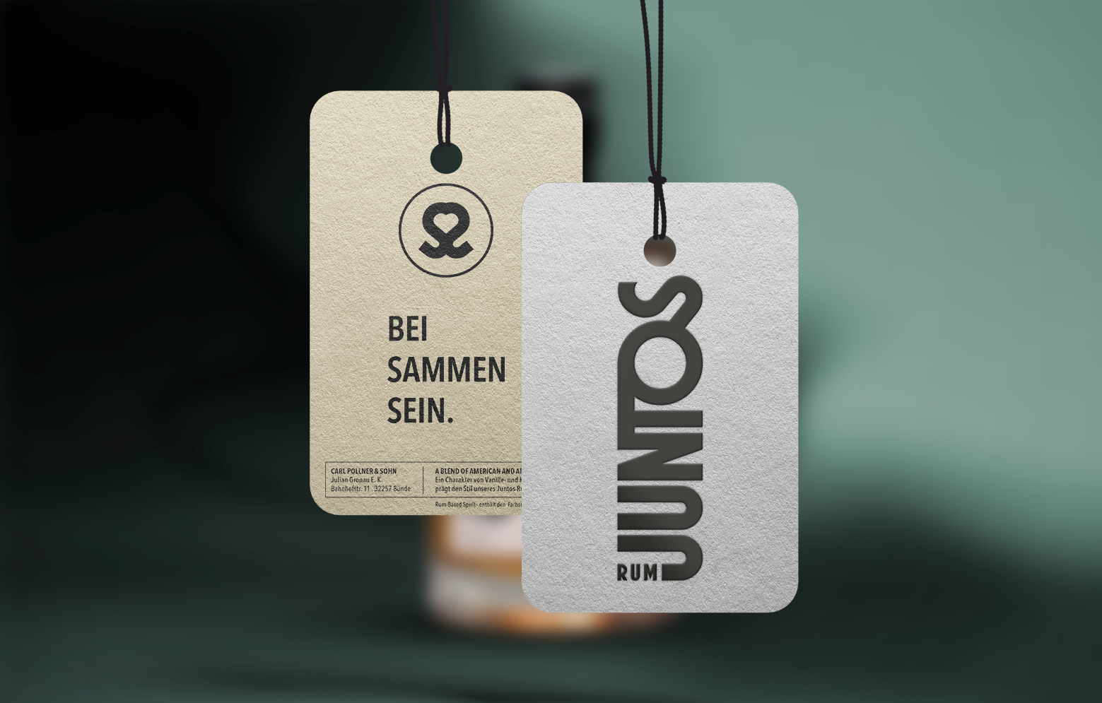 Das JUNTOS-Rum-Hangtag vor einem unscharfen Bild von einer Rumflasche.